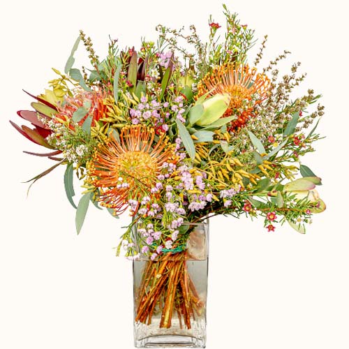 Multicoloured 'Autumn Sunshine' flowers in a small glass vase